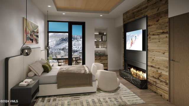 bedroom with a mountain view, a tray ceiling, a large fireplace, and light wood-type flooring