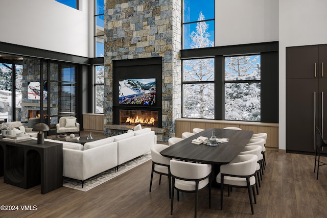 living room featuring dark hardwood / wood-style floors, a towering ceiling, plenty of natural light, and a fireplace