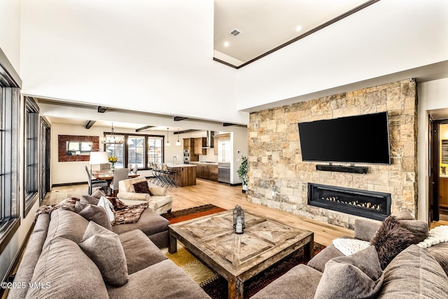 481 Hunters View Ln, Eagle, CO 81631 - living room featuring a fireplace, a chandelier, a high ceiling, light hardwood / wood-style floors, and beam ceiling