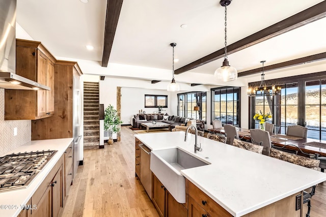 481 Hunters View Ln, Eagle, CO 81631 - kitchen featuring pendant lighting, stainless steel gas stovetop, sink, a kitchen island with sink, and wall chimney exhaust hood