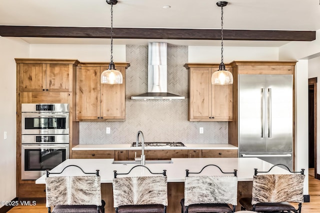 481 Hunters View Ln, Eagle, CO 81631 - kitchen featuring wall chimney exhaust hood, a breakfast bar, sink, hanging light fixtures, and appliances with stainless steel finishes
