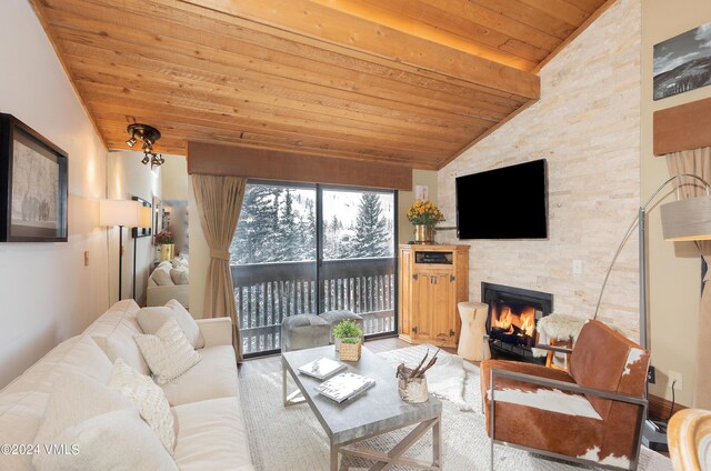 living room featuring lofted ceiling, wood ceiling, and a stone fireplace