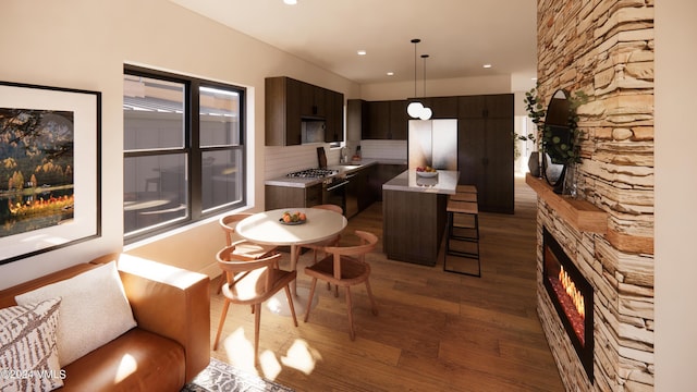 kitchen with a breakfast bar area, refrigerator, dark brown cabinets, dark hardwood / wood-style floors, and a center island