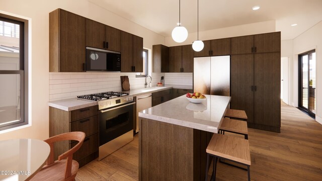 kitchen with pendant lighting, stainless steel appliances, a center island, and light hardwood / wood-style floors