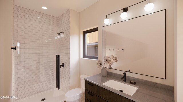 bathroom with vanity, toilet, and tiled shower