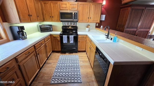 000149 Willis Pl Unit 140, Beaver Creek, CO 81620 - kitchen with black appliances, a sink, tile counters, a peninsula, and light wood-style flooring