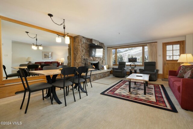 living room featuring an inviting chandelier and a stone fireplace