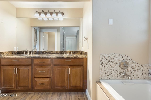 bathroom with hardwood / wood-style flooring, vanity, and a washtub