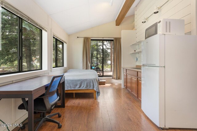 bedroom with lofted ceiling with beams, light hardwood / wood-style floors, and white fridge