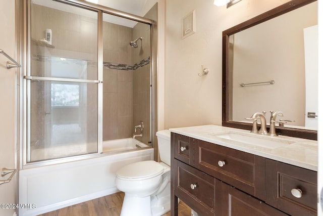 full bathroom featuring vanity, hardwood / wood-style flooring, shower / bath combination with glass door, and toilet