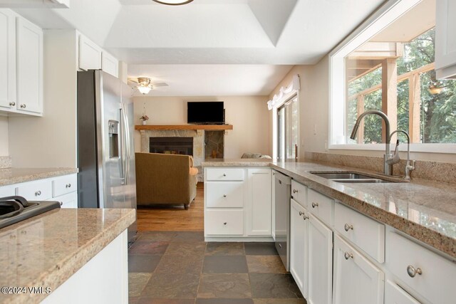 kitchen with sink, ceiling fan, stainless steel appliances, light stone countertops, and white cabinets