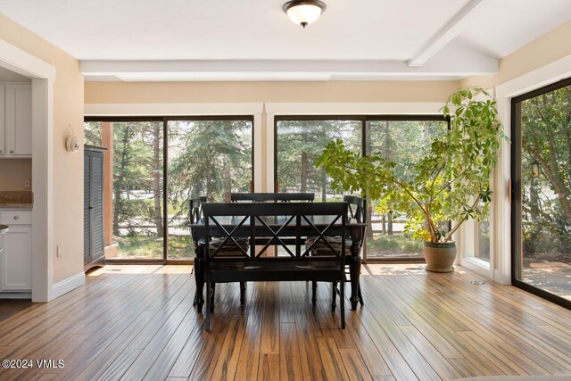 dining area with lofted ceiling with beams and hardwood / wood-style floors