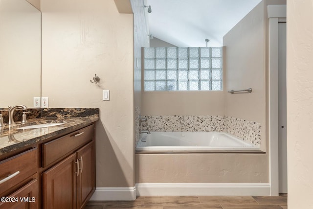 bathroom with vanity, wood-type flooring, and a tub to relax in