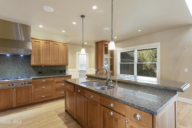 88 E Double Hitch, Eagle, CO 81631 - kitchen featuring a sink, wall chimney range hood, stainless steel gas stovetop, light wood-style flooring, and a kitchen island with sink