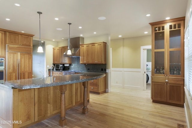 88 E Double Hitch, Eagle, CO 81631 - kitchen featuring wall chimney exhaust hood, light wood-style floors, paneled fridge, brown cabinetry, and recessed lighting