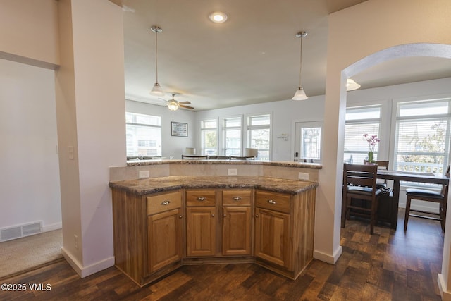 44 Salmon Loop, Gypsum, CO 81637 - kitchen with brown cabinets, a peninsula, arched walkways, ceiling fan, and dark wood-style flooring