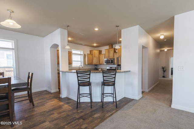 44 Salmon Loop, Gypsum, CO 81637 - kitchen with appliances with stainless steel finishes, arched walkways, baseboards, hanging light fixtures, and dark wood-type flooring