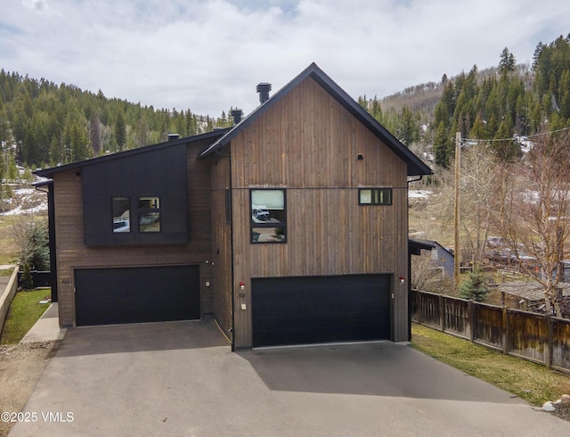 1133 Main St, Minturn, CO 81645 - view of front of house featuring a garage, fence, aphalt driveway, and a view of trees