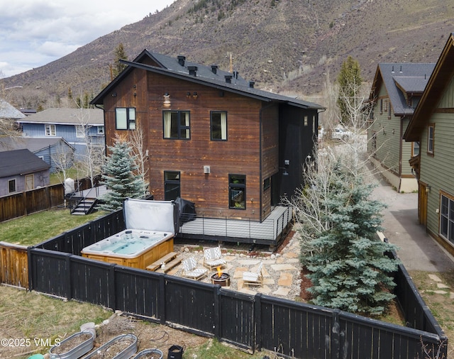 1133 Main St, Minturn, CO 81645 - rear view of house featuring a deck with mountain view, a fenced backyard, and a hot tub