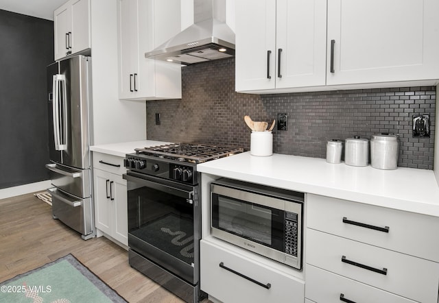1133 Main St, Minturn, CO 81645 - kitchen featuring appliances with stainless steel finishes, light wood-style floors, decorative backsplash, and wall chimney exhaust hood