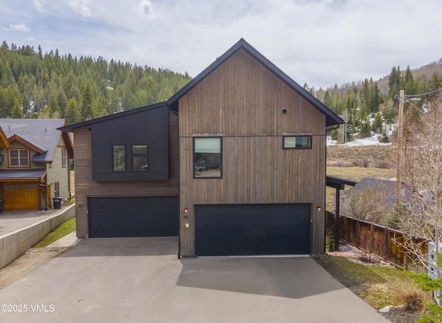 1133 Main St, Minturn, CO 81645 - view of front of home featuring driveway, fence, a wooded view, and a garage