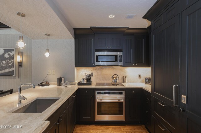 130 Daybreak Rdg Unit Hs640, Avon, CO 81620 - kitchen featuring appliances with stainless steel finishes, light wood-type flooring, decorative light fixtures, a peninsula, and light stone countertops