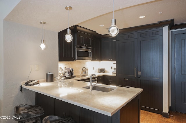 130 Daybreak Rdg Unit Hs640, Avon, CO 81620 - kitchen with stainless steel microwave, a peninsula, a breakfast bar, light countertops, and light wood-style flooring