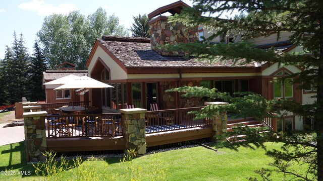 rear view of house with a deck and a lawn