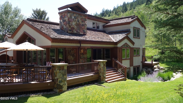 rear view of property with a wooden deck and a lawn