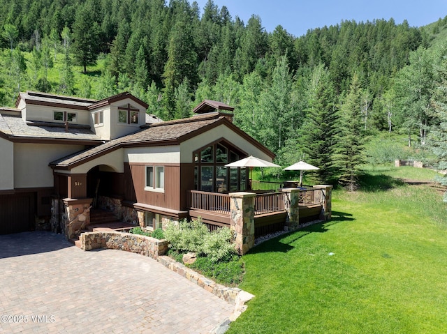 51 Hillside Ct W, Edwards, CO 81632 - view of front of home featuring a view of trees, a front lawn, a wooden deck, and stone siding