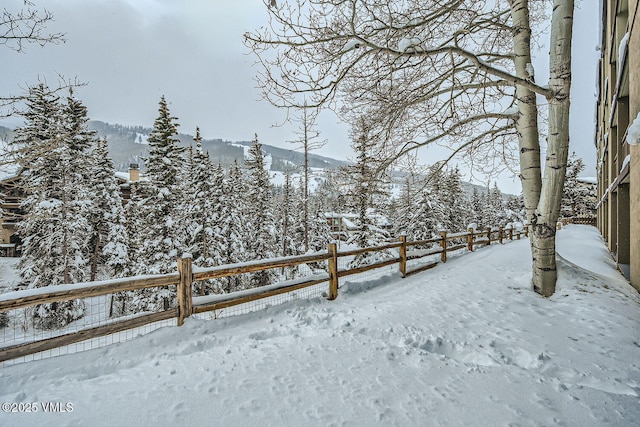 snowy yard with fence and a mountain view