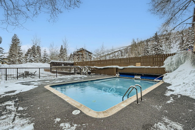 snow covered pool with a fenced backyard and a fenced in pool