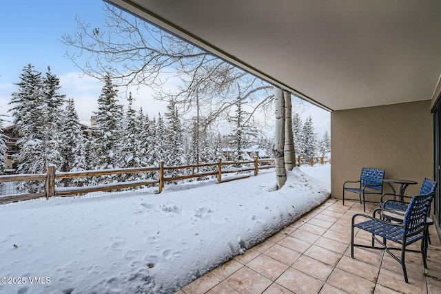 snow covered patio featuring fence