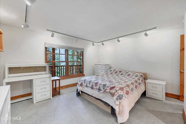 carpeted bedroom featuring track lighting