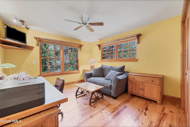 interior space with a ceiling fan, baseboards, plenty of natural light, and light wood-style flooring