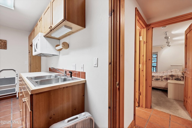 kitchen with light countertops, light tile patterned floors, a sink, and white microwave
