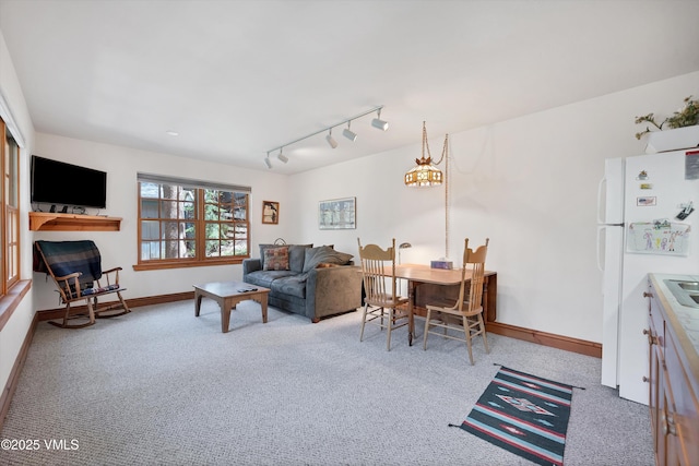 carpeted living room featuring track lighting and baseboards