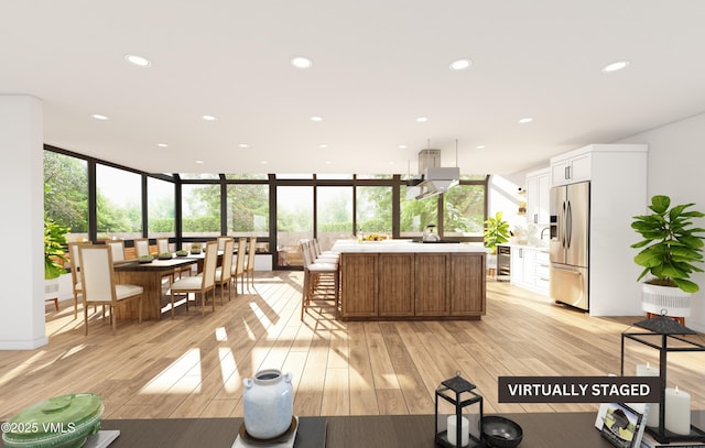 kitchen featuring light hardwood / wood-style flooring, white cabinetry, stainless steel refrigerator with ice dispenser, expansive windows, and a kitchen island