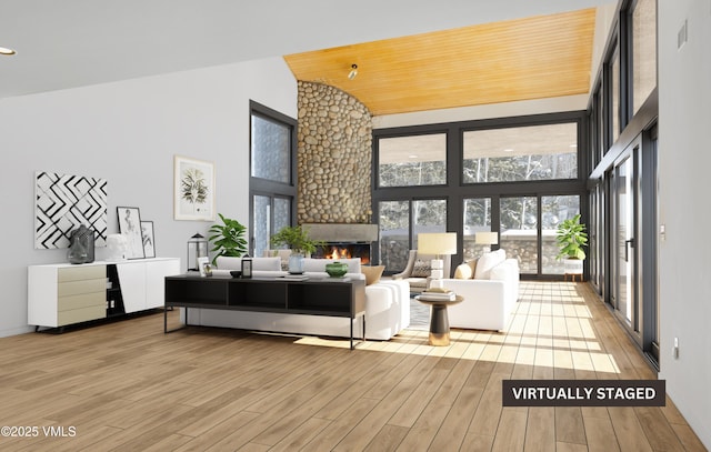 living room featuring a large fireplace, high vaulted ceiling, light hardwood / wood-style flooring, and a wealth of natural light