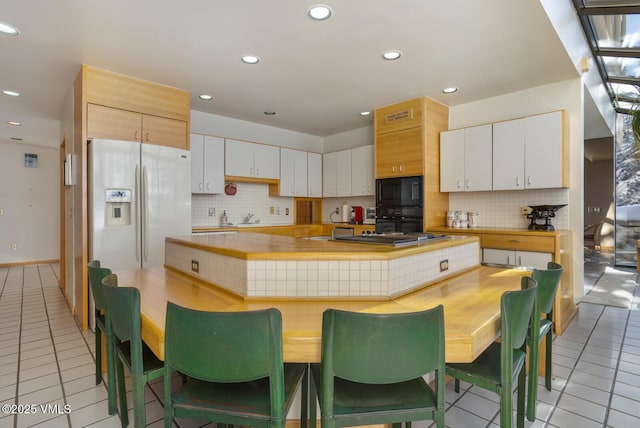 kitchen with light tile patterned flooring, black appliances, and white cabinets