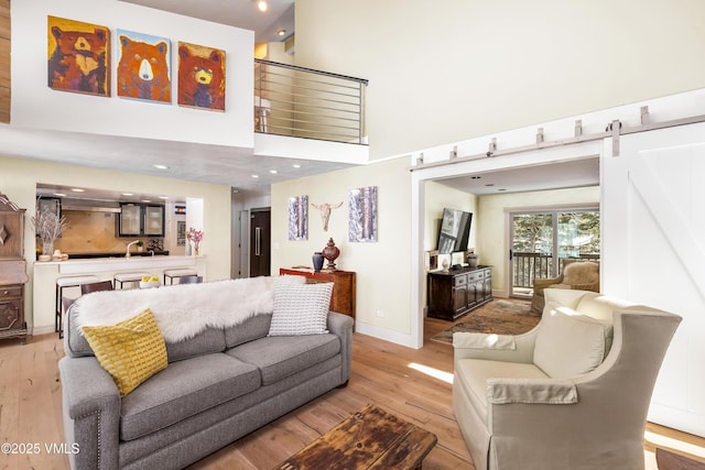 4524 Meadow Dr Unit 905, Vail, CO 81657 - living room featuring light wood finished floors, a barn door, a high ceiling, baseboards, and recessed lighting