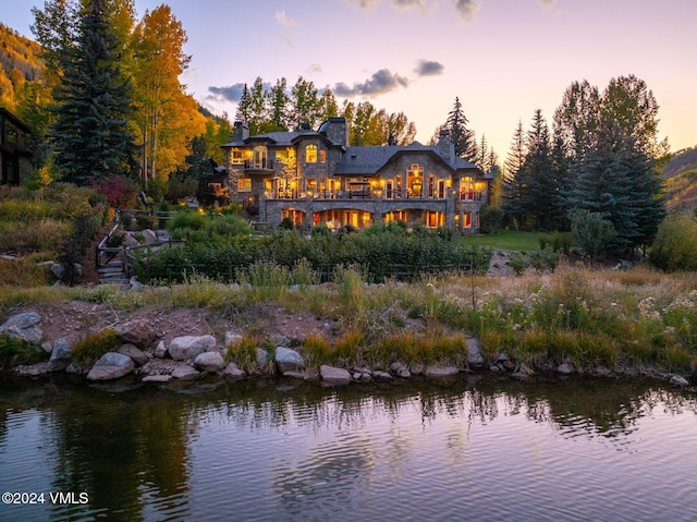 back house at dusk featuring a water view