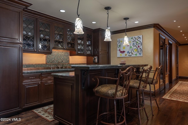 bar featuring crown molding, dark brown cabinets, pendant lighting, and dark wood-type flooring