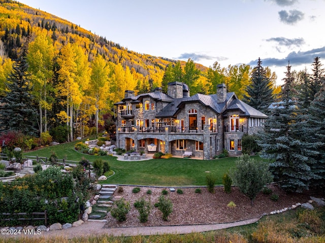 back of house with a patio, a balcony, a yard, and a mountain view