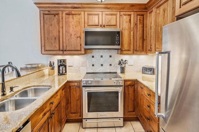 4031 Bighorn Rd Unit 9-H, Vail, CO 81657 - kitchen with appliances with stainless steel finishes, brown cabinets, backsplash, light stone countertops, and light tile patterned flooring