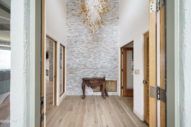 hallway with a towering ceiling and light wood finished floors