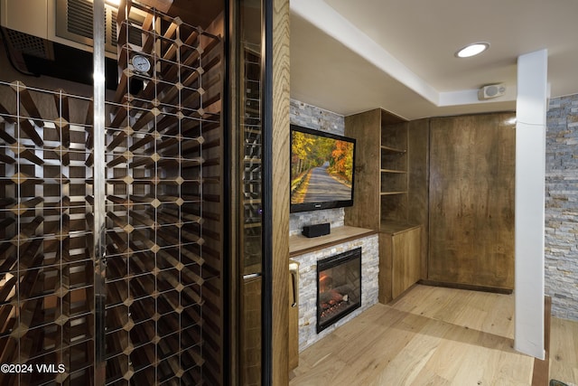 wine cellar with light wood-type flooring and a glass covered fireplace