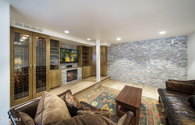 living area with light wood finished floors, a glass covered fireplace, visible vents, and recessed lighting