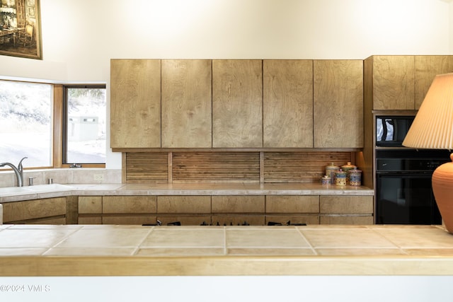 kitchen featuring a sink, tile countertops, and black appliances