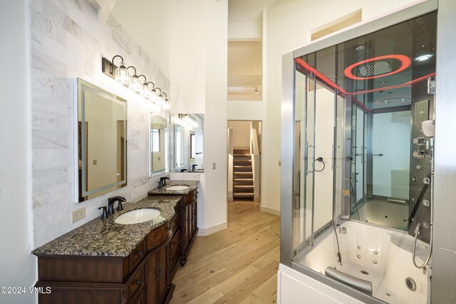 bathroom featuring double vanity, a sink, backsplash, and wood finished floors